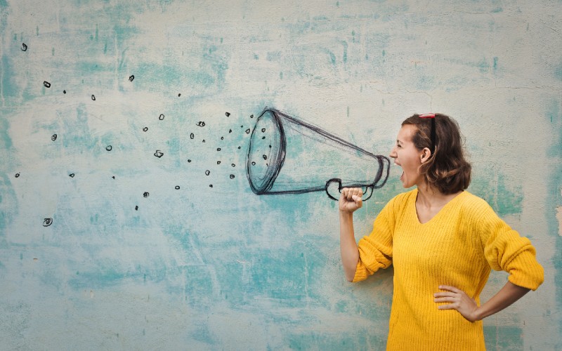 Person hält ein Magafon in der Hand und schreit hinein