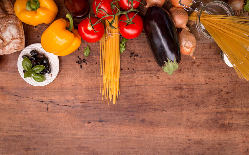 Zutaten für mediterranes Gericht, es gibt Zwiebeln, Nudeln, Paprika, Tomaten und Oliven
