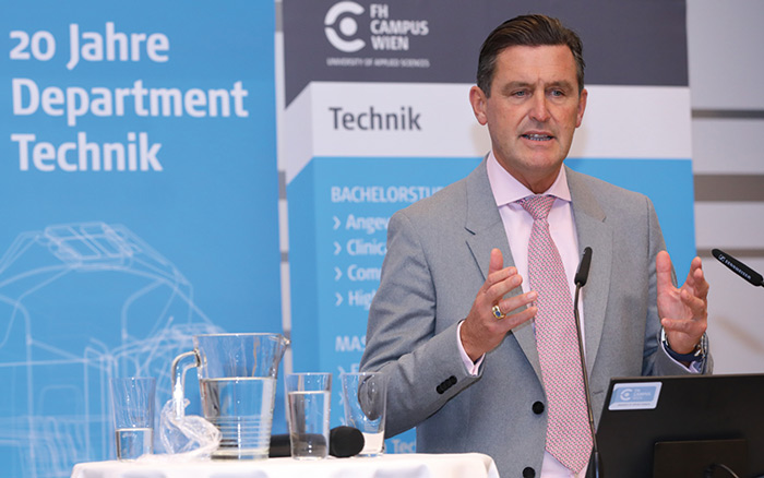 © Schedl / FH Campus Wien Peter Hanke spricht zu einem Publikum und gestikuliert dabei leicht mit seinen Händen