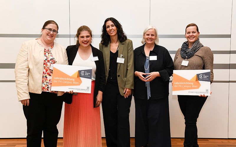 Gruppenfoto mit fünf Personen wovon zwei eine Lehreinrichtungstafel halten