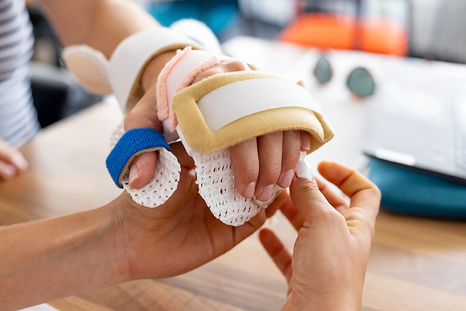 Zwei Hände, eine Hand ist in einer Schiene. 