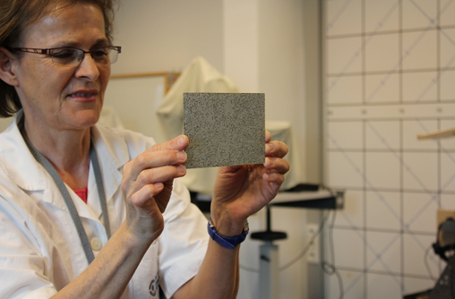 Die Vortragende hält, auf Augenhöhe, ein Lang-Stereotest hoch, auf denen die Studierende Prüfbilder erkennen soll. Der Lang-Stereotest ist eine postkartengroßen und unterschiedlichen grau und schwarz Tönen gepunktete Fläche.