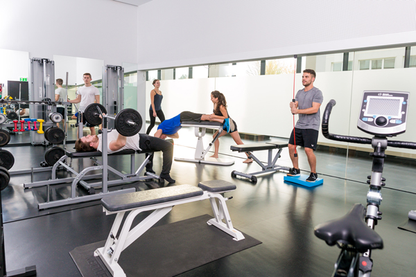 Fitnessraum mit Studierenden die unterschiedliche Fitness- und Cardiogeräte ausprobieren.