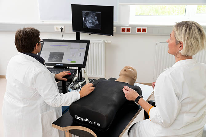 Zwei Personen üben an einer Puppe eine Ultraschallsimulation