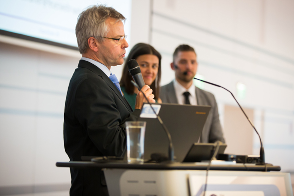 Zwei Herren und eine Dame am Rednerpult