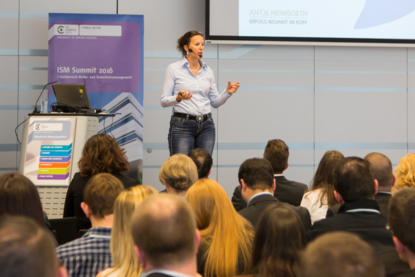 Dame mit Mikrofon redet vor Publikum