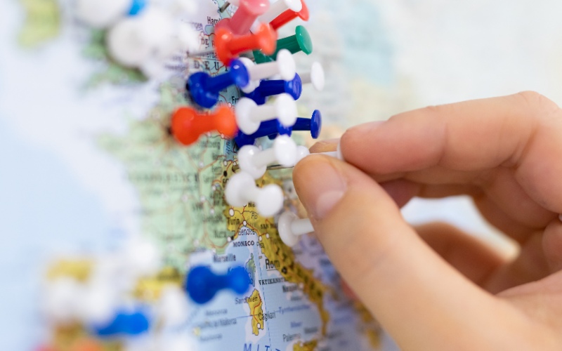 © HCW/Schedl Eine Stecknadel wird auf eine Landkarte platziert