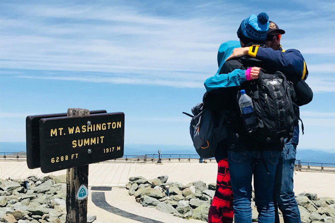 Zwei sich umarmenden Personen am Mount Washington Summit