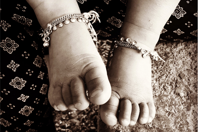 Zwei Kinderfüße mit schmuckhaften Ketten
