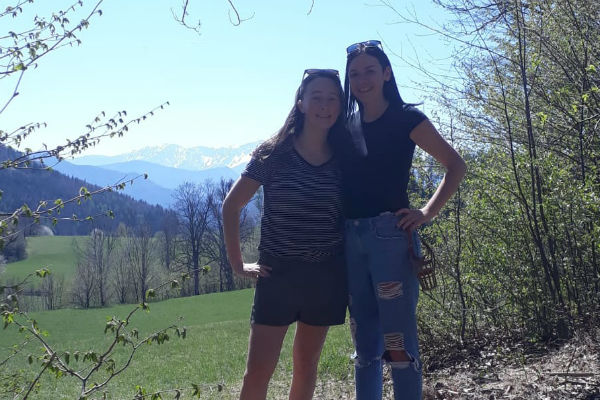 Anna mit Freundin in der Natur und schneebedeckte Berge im Hintergrund