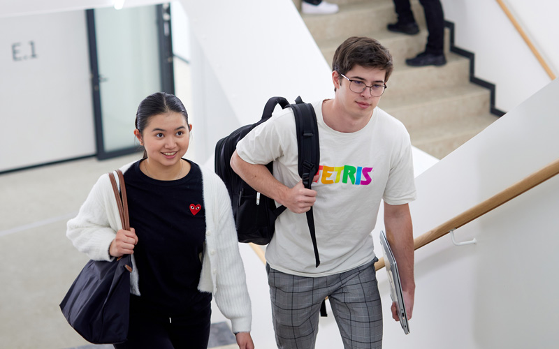 Zwei Studierende gehen die Stiege im House of Science and Engineering der Hochschule Campus Wien hoch
