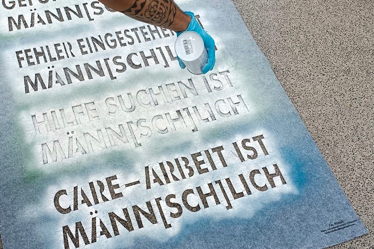 Verschiedene Slogans mit "Männ[sch]lich werden auf den Boden gesprayt