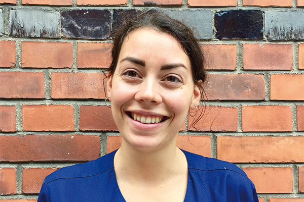 Junge Dame lächelnd vor Backsteinwand