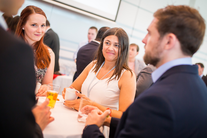 Gruppe von Leuten unterhält sich an Stehtisch mit Getränken in den Händen