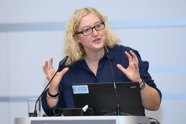 Dame mit Brille und blonden schulterlangen Haaren am Rednerpult