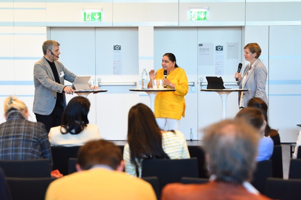 Drei Personen an Stehtischen