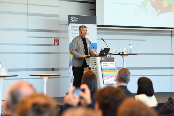 Herr mit grauem Sacko am Rednerpult