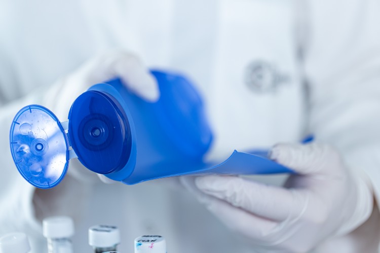 Blaue Verpackung wird auseinandergenommen, Person trägt Handschuhe