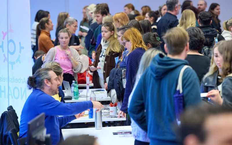 Personen auf der Messe, die sich an Ständen beraten lassen