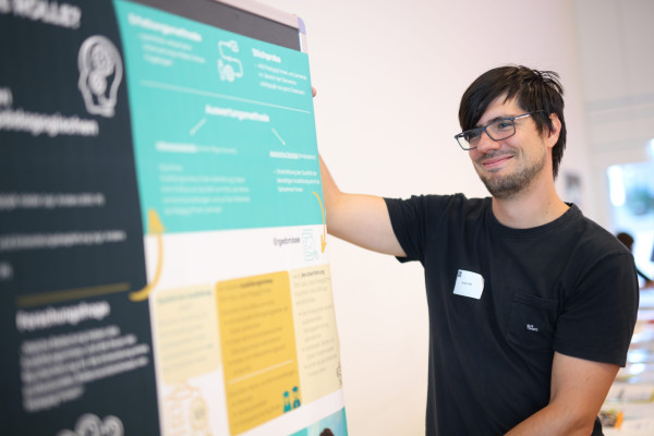 Mann steht vor einem Poster