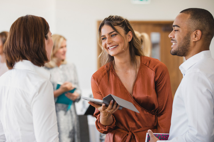 3 Personen im freundlichen Gespräch, im Hintergrund weitere Menschen