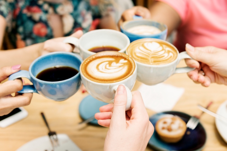 © Rawpixel/iStock.com Fünf Tassen mit Kaffee, mit denen angeprostet wird