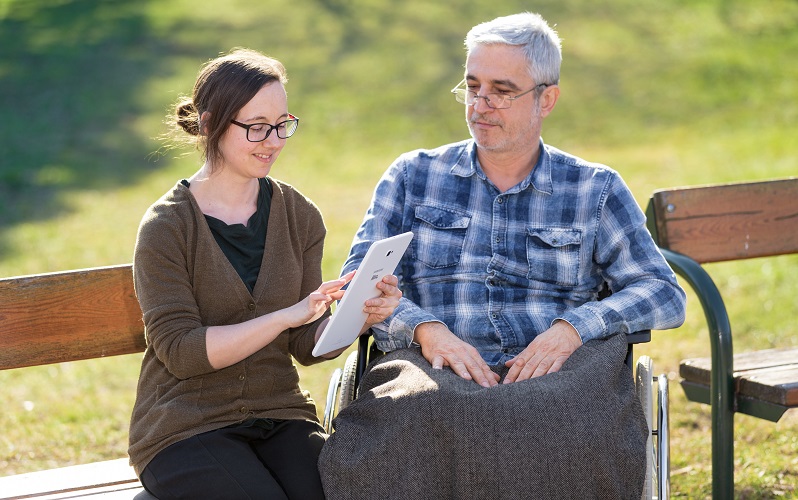 © HCW/Ludwig Schedl Mann im Rollstuhl, Frau mit Tablet in der Hand