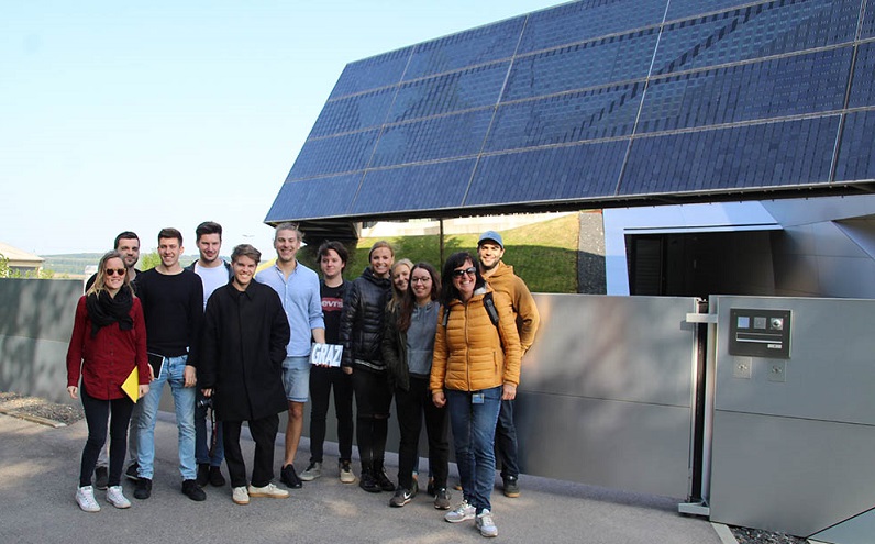 Männer und Frauen vor einem Gebäude mit Photovoltaik-Fassade