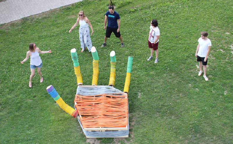 Studierende vor einem bunten Sitzmöbel in Handform im Mensagarten