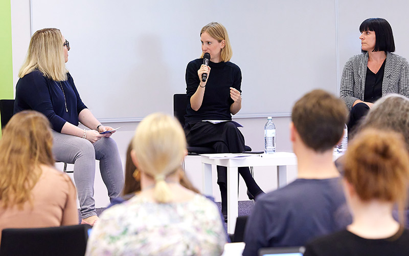 three people sit on stage and discuss