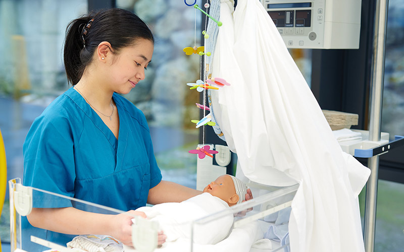 Student holds a baby in her hand
