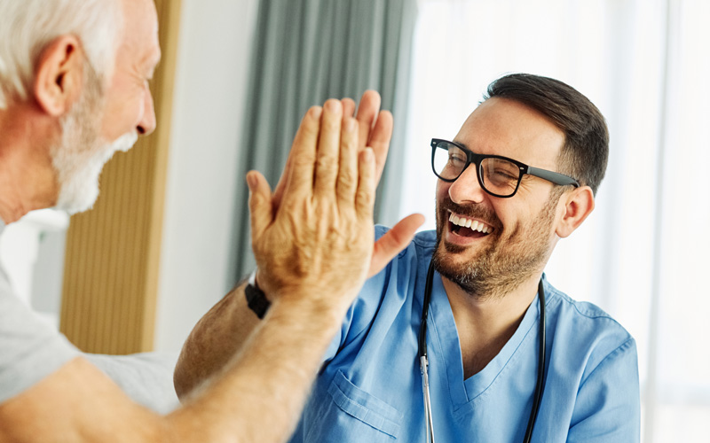 Gesundheits- und Krankenpflegeperson klatscht mit einer ältereen Person die Hand ab