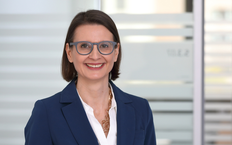 (c) FH Campus Wien / Schedl Lächelnde Frau mit Brille vor einer Glaswand