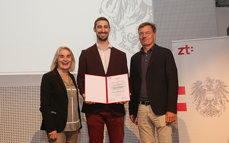 Junger Mann (Simon Kaufmann) hält strahlend seine Urkunde in die Kamera.