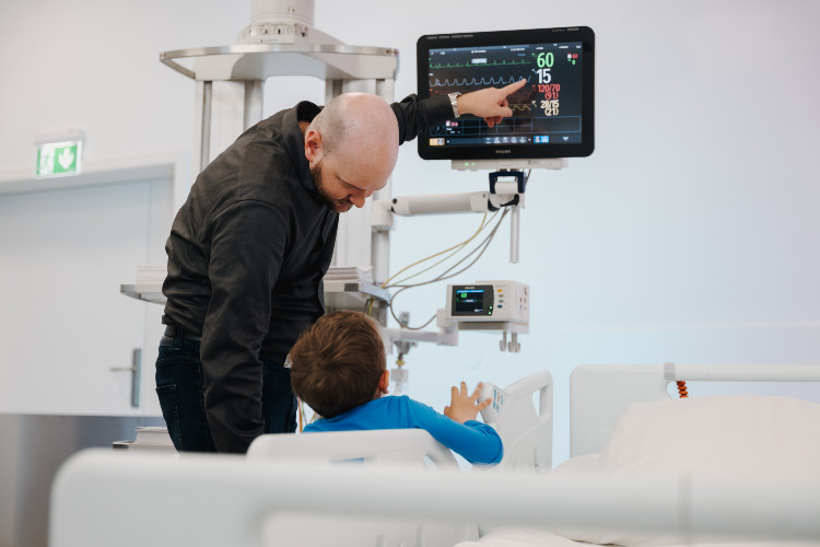 Vater und Sohn im OPIC der Hochschule Campus Wien, bei der Betrachtung eines technischen Geräts. 