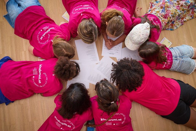 © Hochschule Campus Wien/Schedl Kinder liegen im Kreis auf dem Boden.